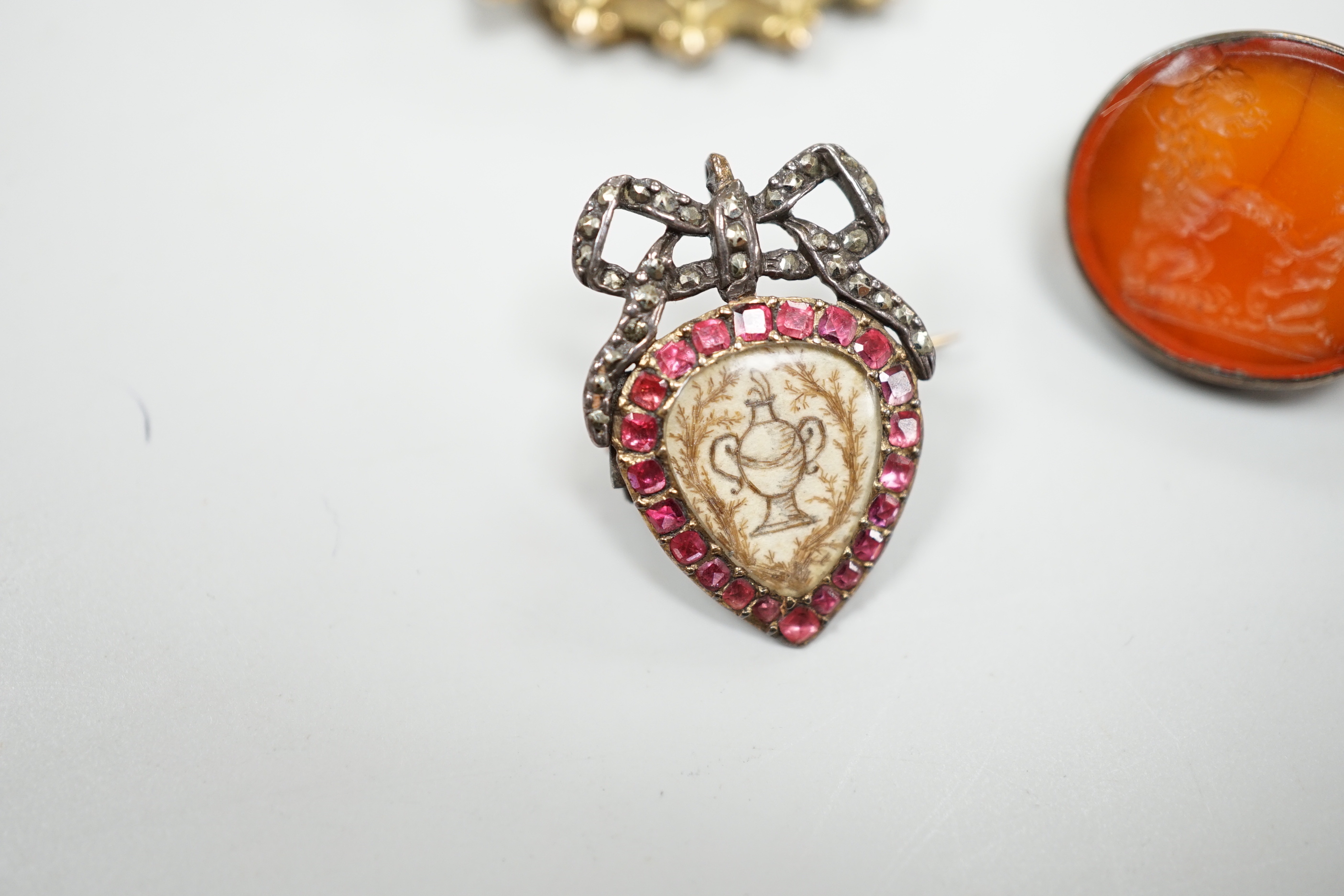 Five assorted antique brooches, comprising an early 19th century foiled ruby and hair work heart shaped brooch, 2.25cm, an early 19th century foiled garnet memorial brooch, 1.75cm, a Victorian unmarked gold oval brooch,